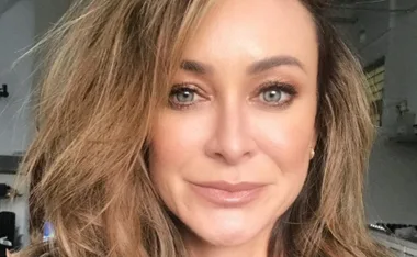 Close-up portrait of a woman with long hair and light eyes, smiling softly.