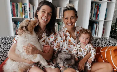 Family in matching pajamas with dog and cat, bookshelf in background.