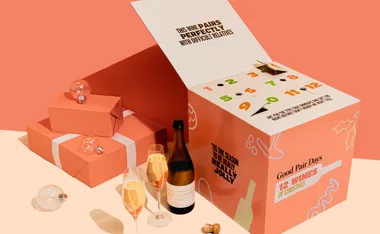 Orange box and gifts with wine, glasses, and holiday-themed text.