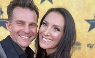 Smiling couple posing together at an event with a yellow star-patterned background.
