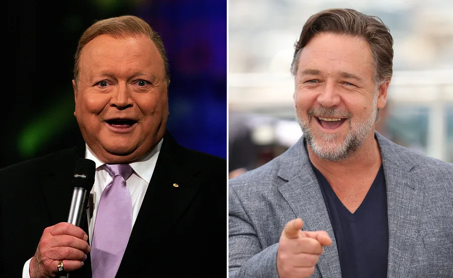 Two men smiling side by side; one is holding a microphone, the other pointing. They are in a biopic discussion.