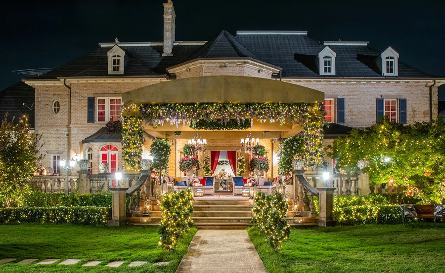 A grand house at night, adorned with vibrant lights and floral decorations, set for a festive or romantic gathering.