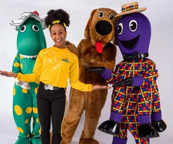 The Yellow Wiggle, Tsehay Hawkins, poses with Wiggles characters Dorothy the Dinosaur, Wags the Dog, and Henry the Octopus.
