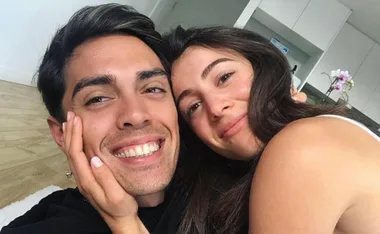 A couple smiling and embracing in a cozy indoor setting.