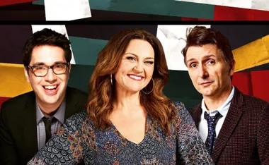 Three smiling hosts from "Would I Lie to You?" in front of a colorful backdrop.