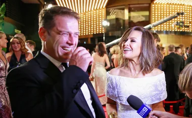 Two people smiling at an event, with lights in the background and a microphone in the foreground.