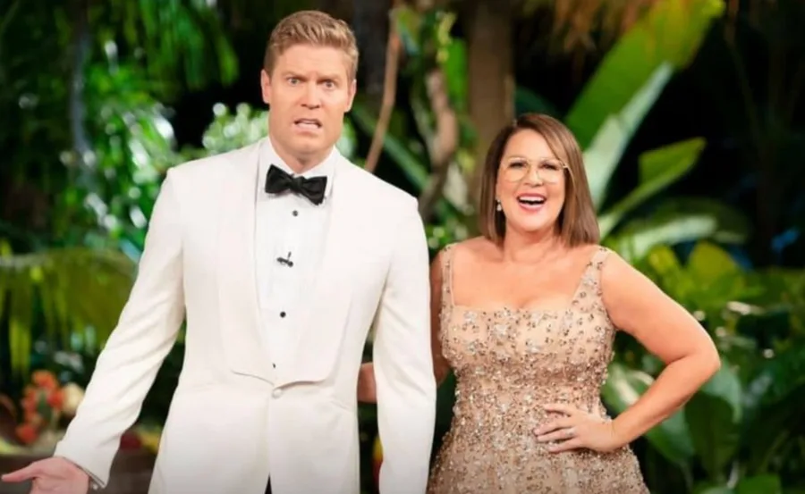 "Two hosts in formal attire stand smiling and posing in a lush jungle setting, suggesting a show announcement."