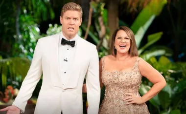 "Two hosts in formal attire stand smiling and posing in a lush jungle setting, suggesting a show announcement."