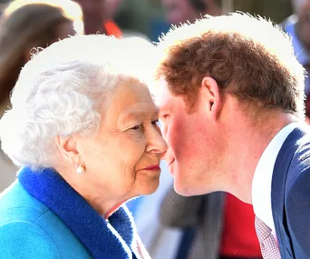 A man in a suit leans in to greet an elderly woman with white hair wearing a blue coat.