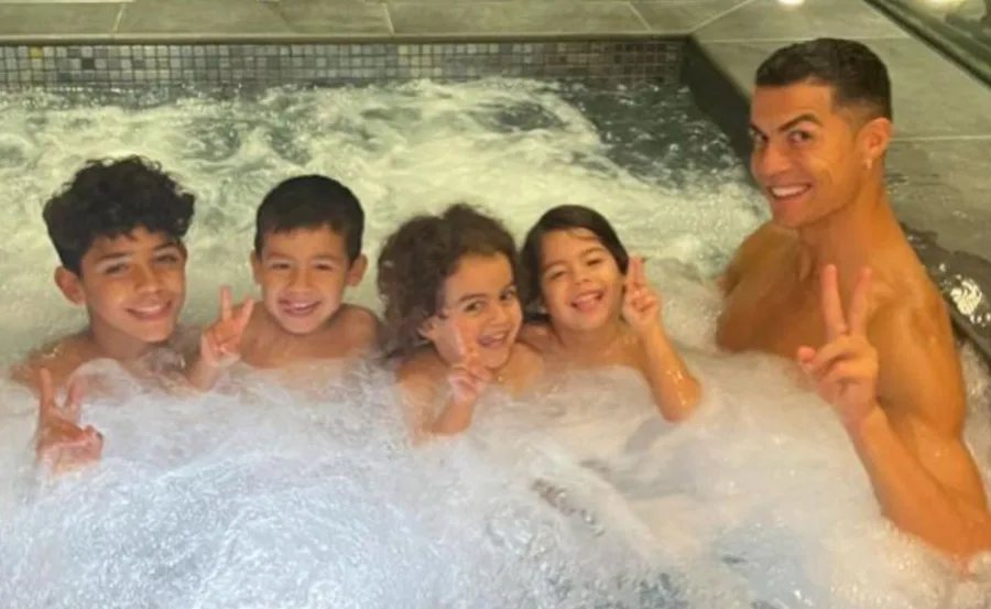 Family in a jacuzzi smiling and holding up peace signs, showing joy and togetherness.