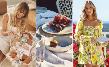 A woman playing with a baby, a fruit-laden table, and another woman holding a book in a floral dress.