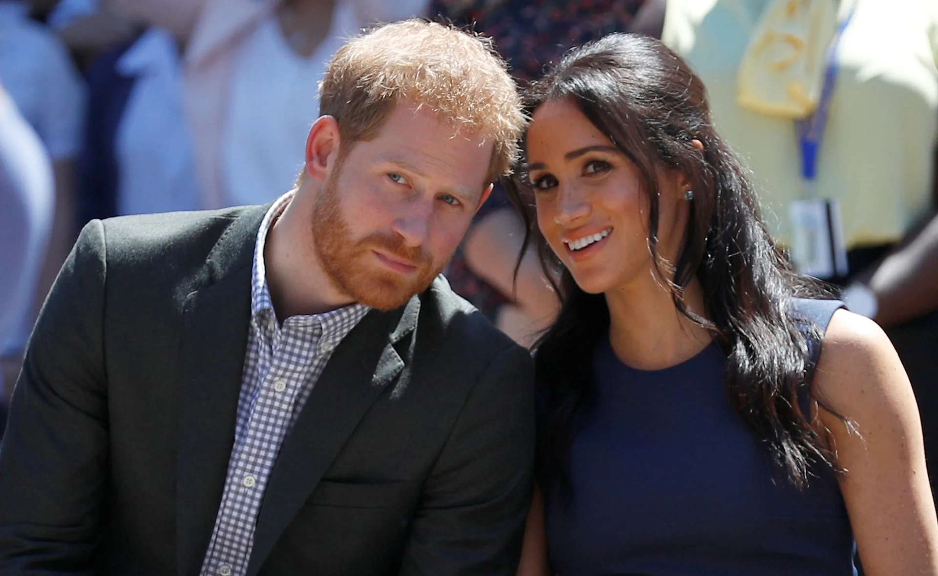 Two people sitting close together at an outdoor event, smiling at the camera.