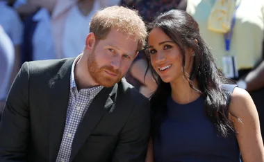Two people sitting close together at an outdoor event, smiling at the camera.