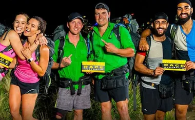 Contestants from The Amazing Race Australia 2022 with race cards, standing in outdoor nighttime setting.