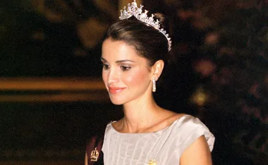 A woman wearing a tiara and elegant attire, smiling.