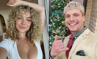 Smiling woman with curly hair in a white top and a man in a beige suit with greenery in the background.