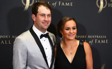 A couple posing at the Sport Australia Hall of Fame event; the man is in a tuxedo and the woman in a black dress.
