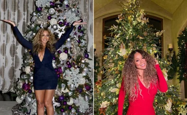 "Two women in front of decorated Christmas trees, one in a navy dress, the other in a red dress, smiling and posing."