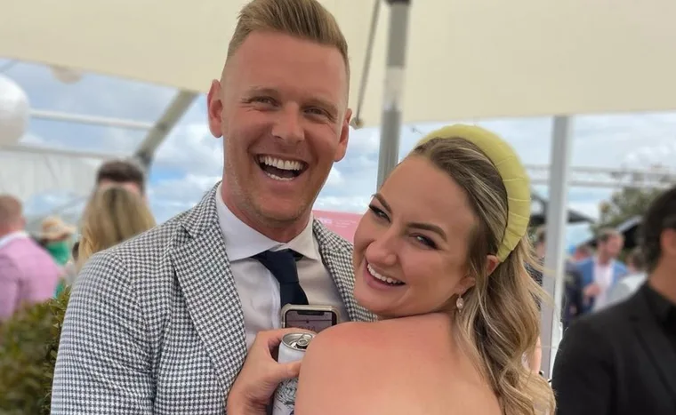 A couple smiling and embracing at an outdoor event.