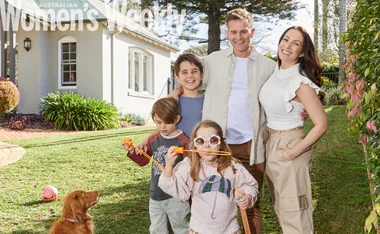 Family of five with a dog in front of a house, kids blowing bubbles, smiling under sunny skies, Australian Women’s Weekly.