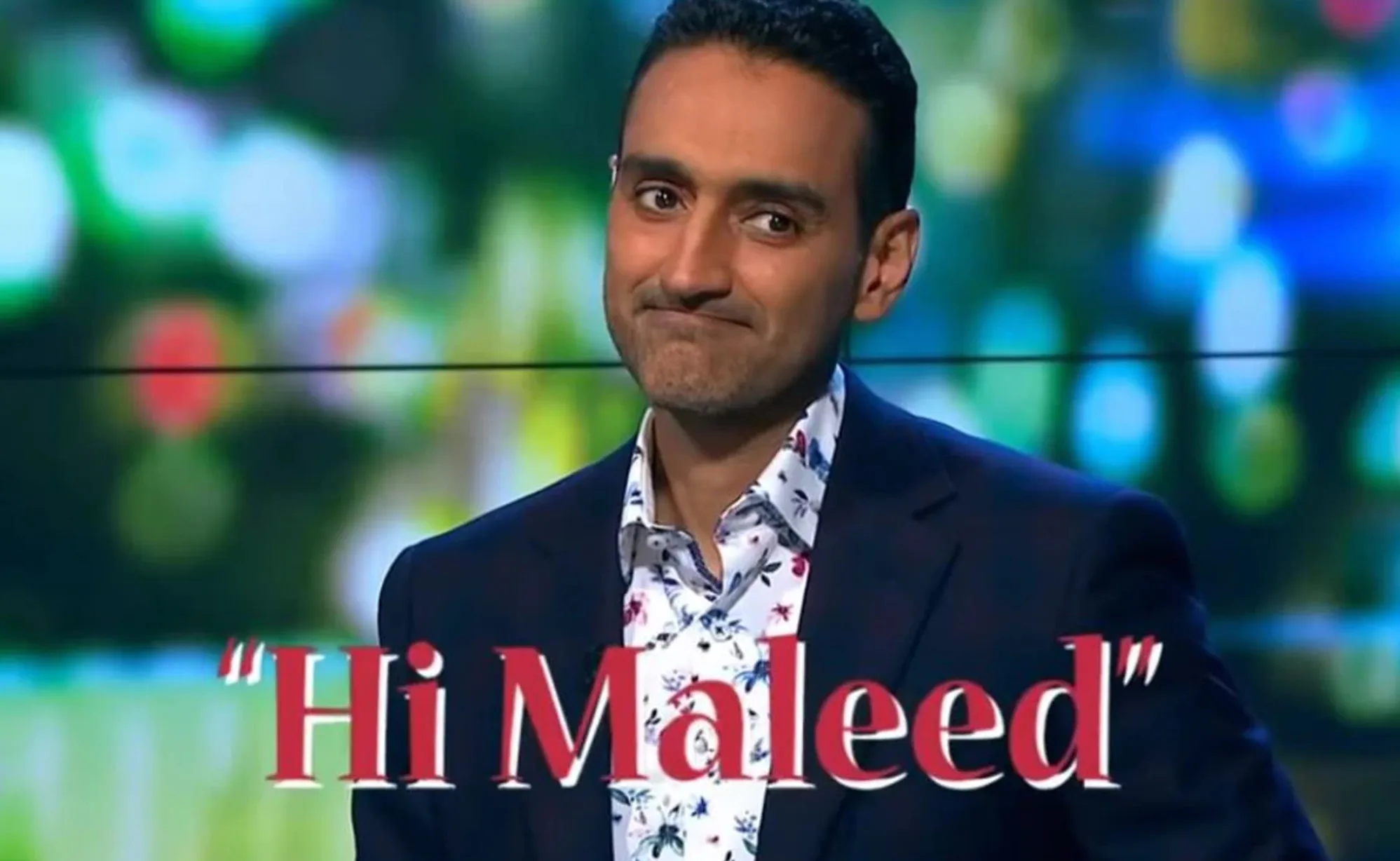Man in suit with floral shirt, text overlay "Hi Maleed," blurred colorful background.