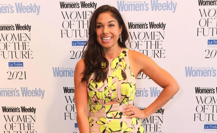 Woman in floral dress smiling at 'Women of the Future' event backdrop.