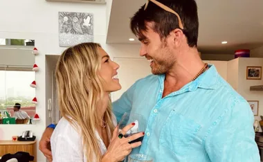 Sam Frost and Nicholas Cartwright smiling at each other warmly indoors.