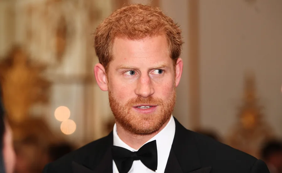 Prince Harry in a tuxedo, looking to the side at a formal event.