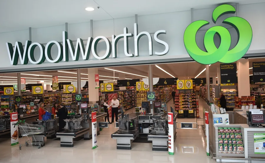 Front entrance of a Woolworths supermarket with checkouts and shoppers inside.