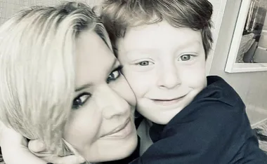 Woman with blonde hair hugging a young boy, both smiling warmly at the camera.