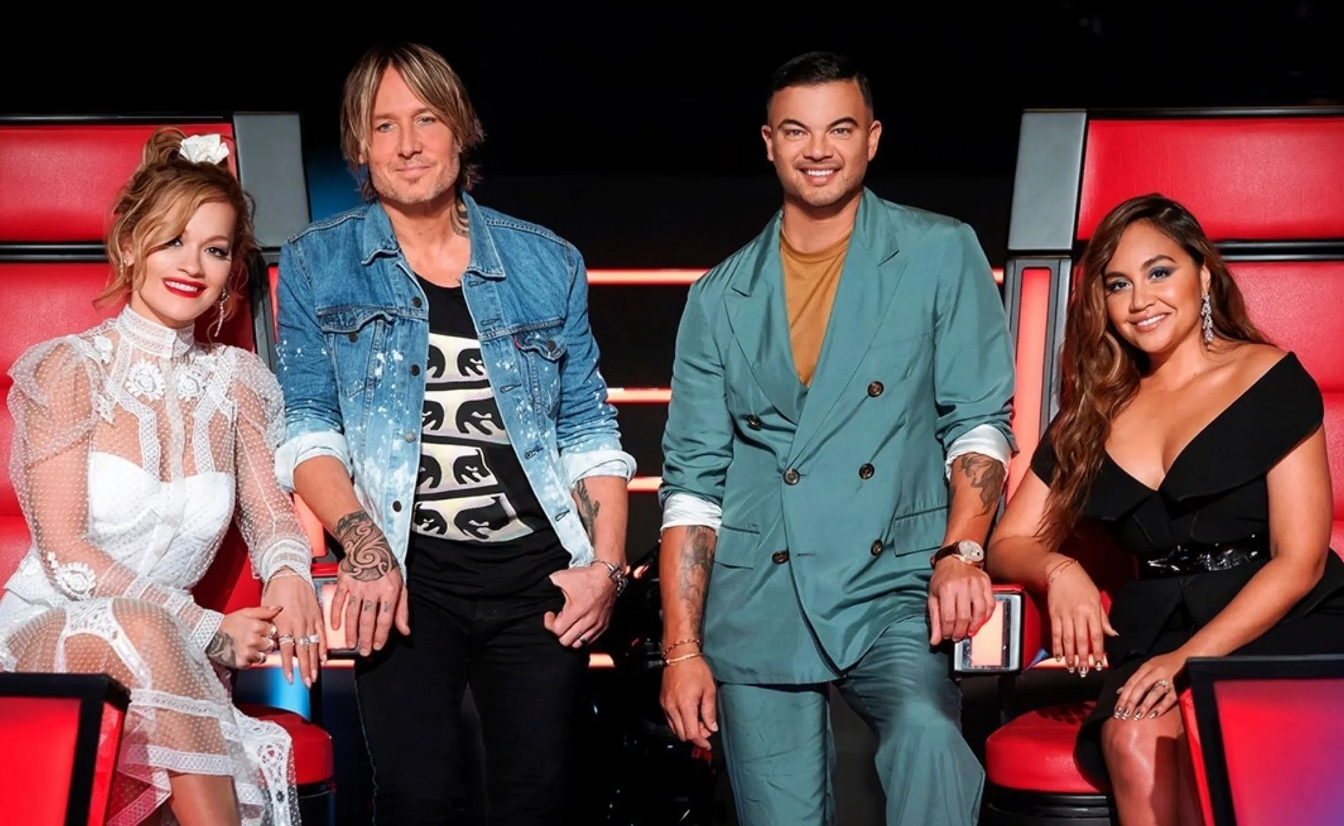 Judges panel from The Voice Generations 2022 seated on red chairs.