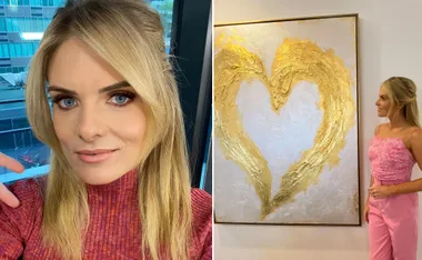 Blonde woman indoors, left in a pink top and right in pink outfit gazing at a gold heart painting on the wall.