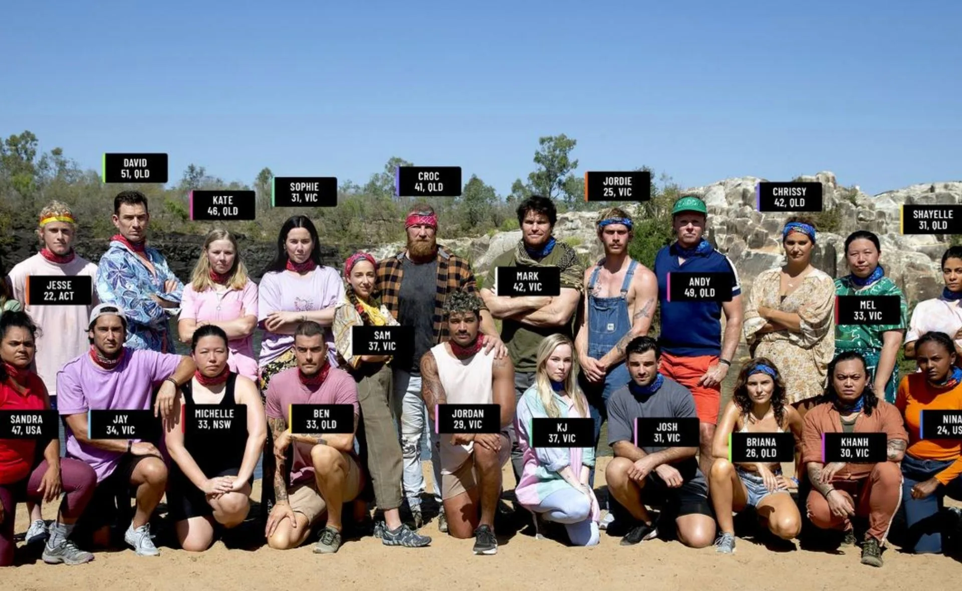 Group photo of Australian Survivor 2022 contestants standing outdoors on sandy terrain.