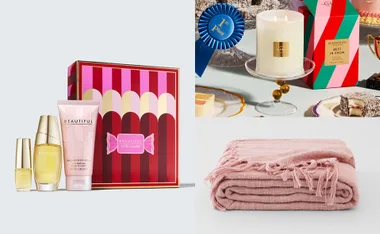 Gift set with Estee Lauder products, scented candle, desserts, and a folded pink blanket.