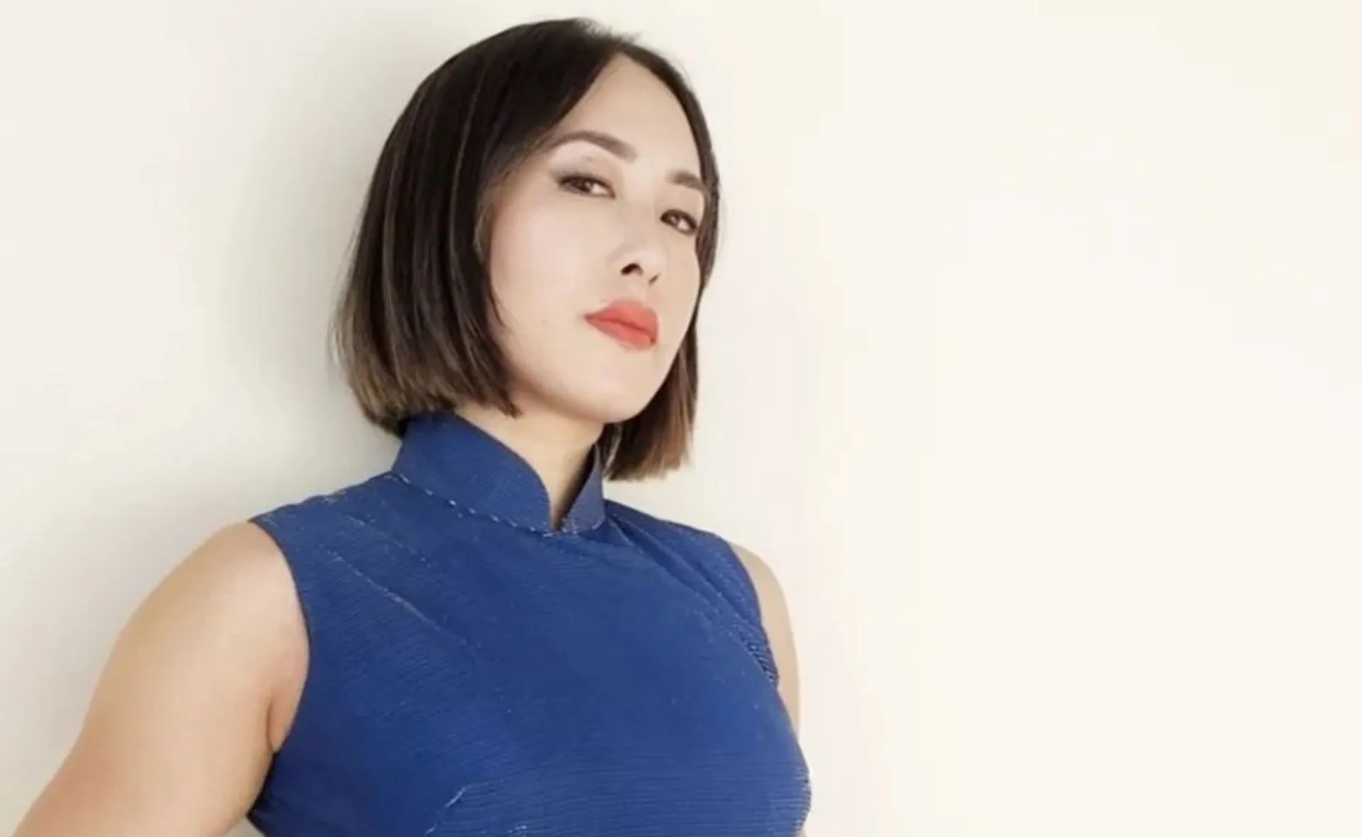 Person in a blue sleeveless top, looking confidently at the camera against a plain background.