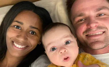 A couple smiles with their baby, capturing a joyful family moment.