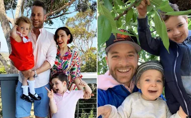 A happy family smiling outdoors, with a man, woman, and two children posing among trees.
