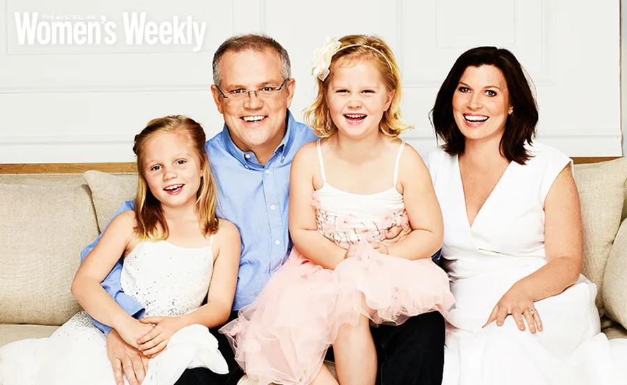 Family smiling together on a couch, dressed in formal attire, featured in The Australian Women's Weekly magazine.