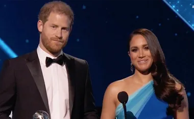 Two individuals in formal attire on stage at the NAACP Image Awards holding a trophy.