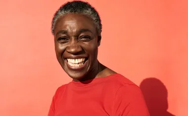 Smiling woman in a red shirt against a bright red background.