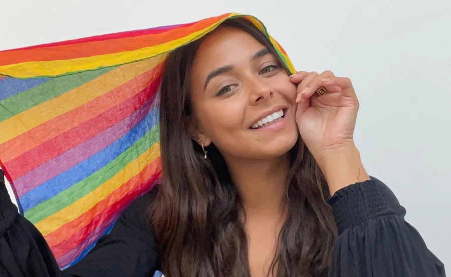 Woman smiling under a rainbow-colored cloth.