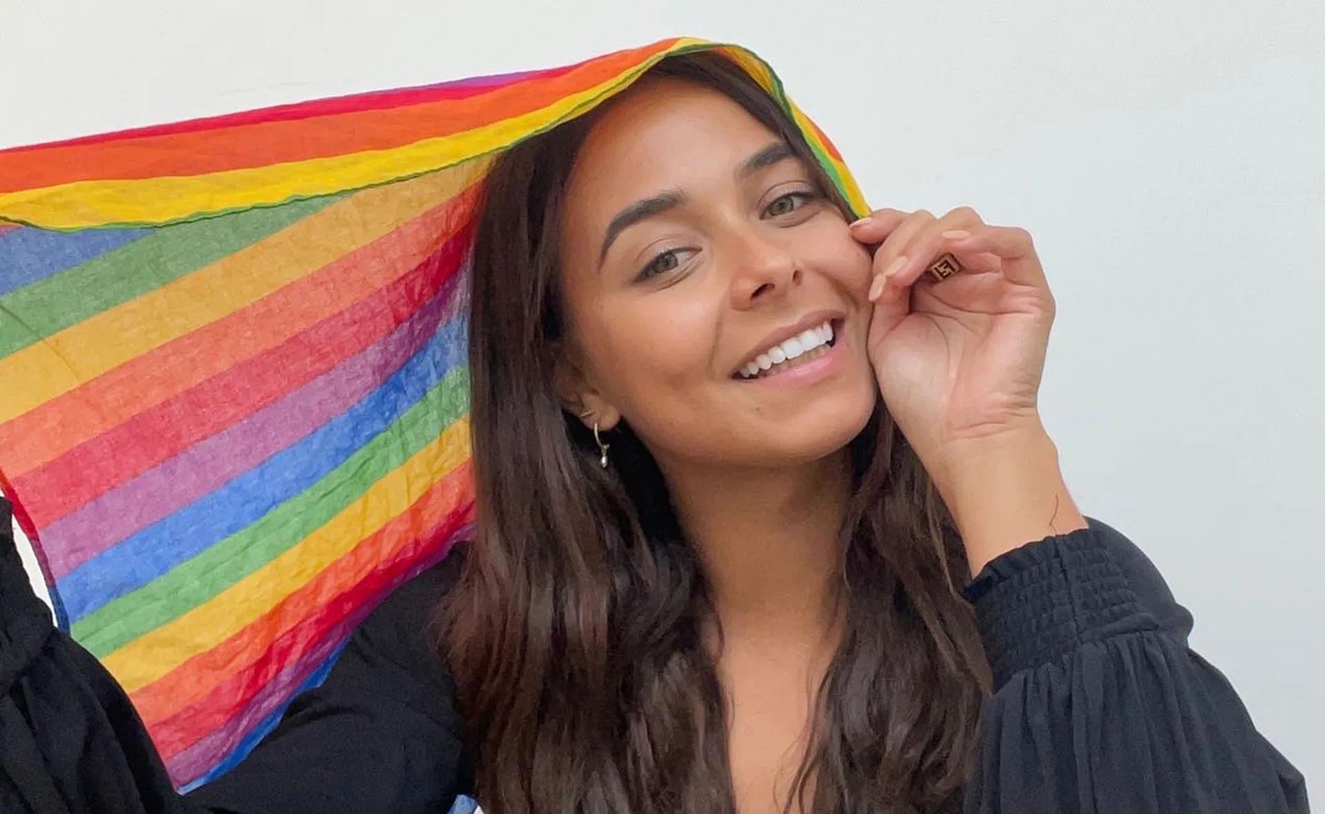 Woman smiling under a rainbow-colored cloth.