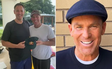 Two men smiling, one holding a hat; man on right in black cap smiling at camera.