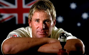 Cricketer with Ashes trophy, Australian flag in background.