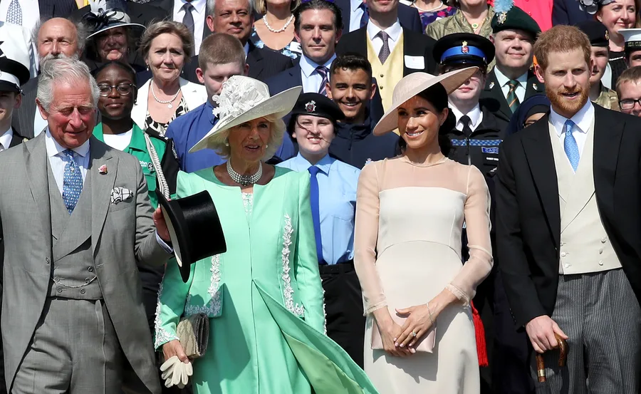 A group of well-dressed individuals smiling, with officials and cadets in the background.
