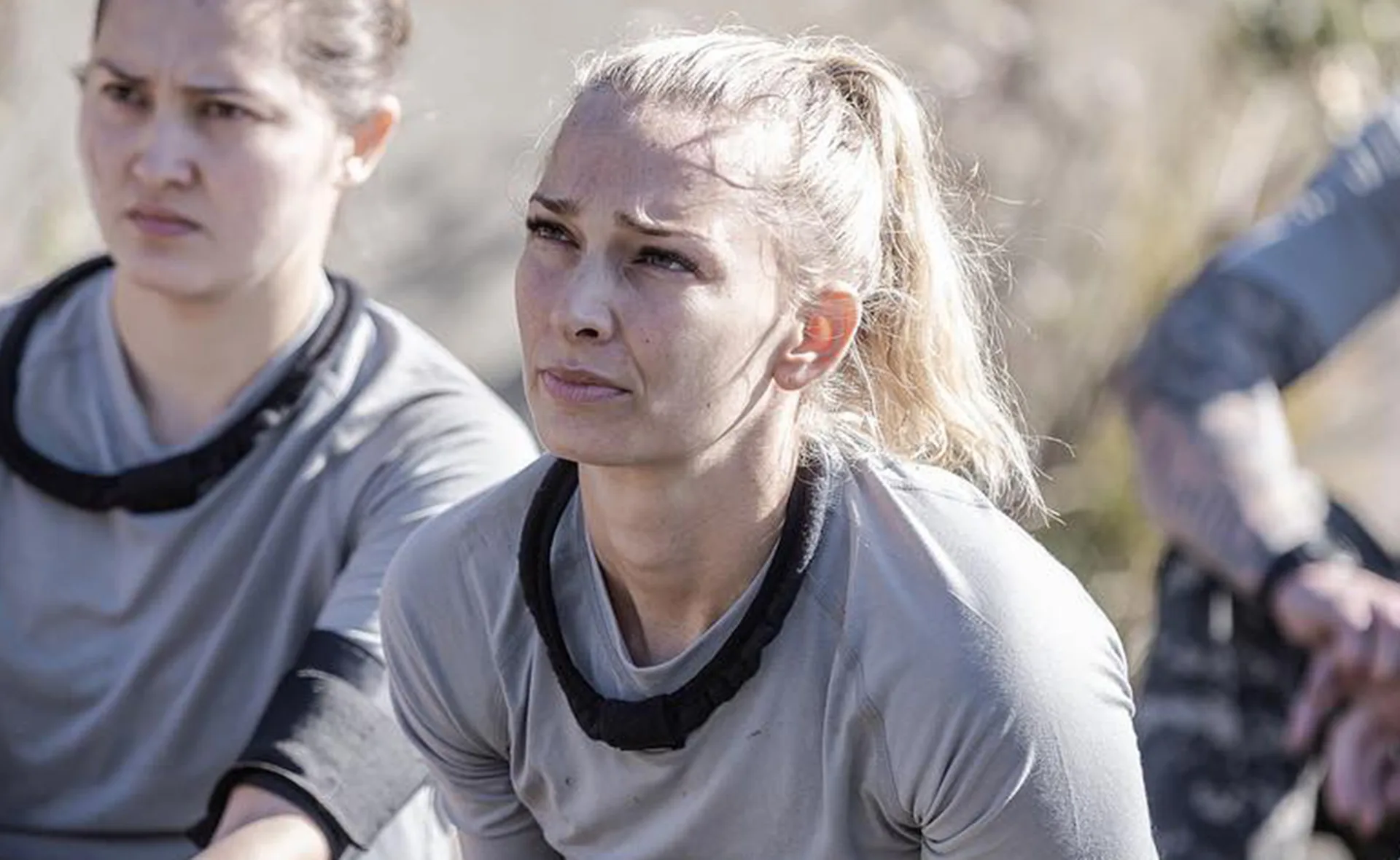 Two people in rugged outdoor clothing appear focused and determined during a challenge or activity.