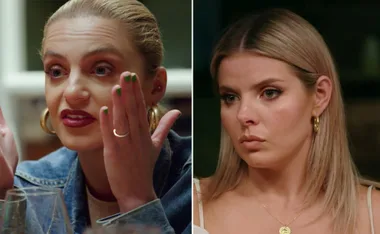 Women having a tense conversation during a dinner, both wearing gold hoop earrings.