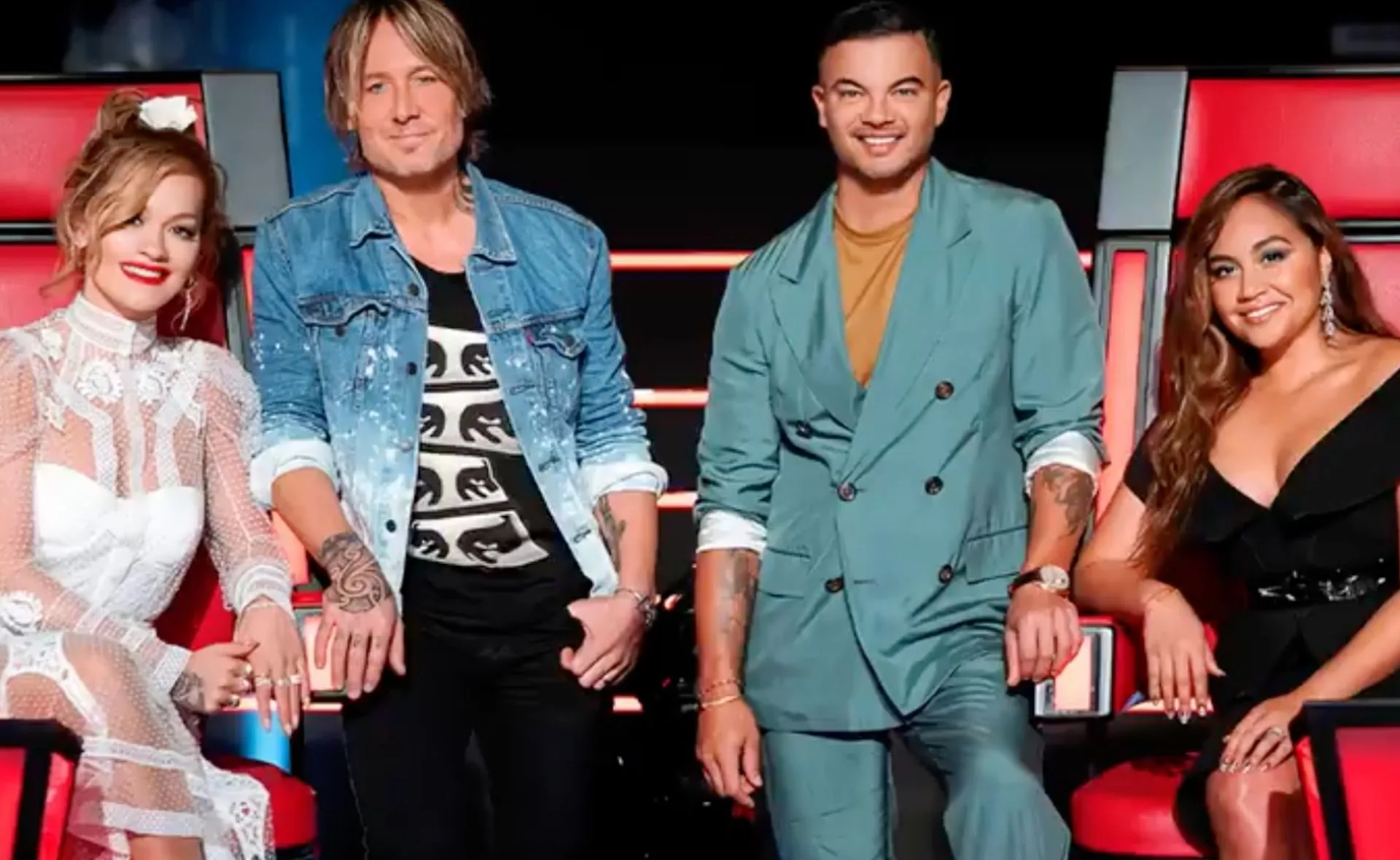 Group of four judges seated in red chairs on a TV show set.