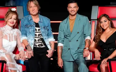 Group of four judges seated in red chairs on a TV show set.