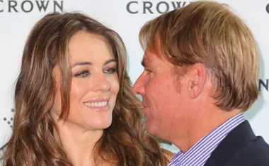 A man and a woman smiling at each other at an event with a Crown logo in the background.